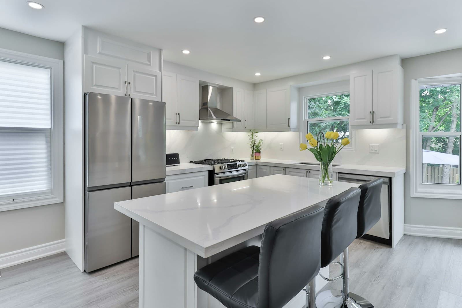 Bright white kitchen with a stainless steel refrigerator and range