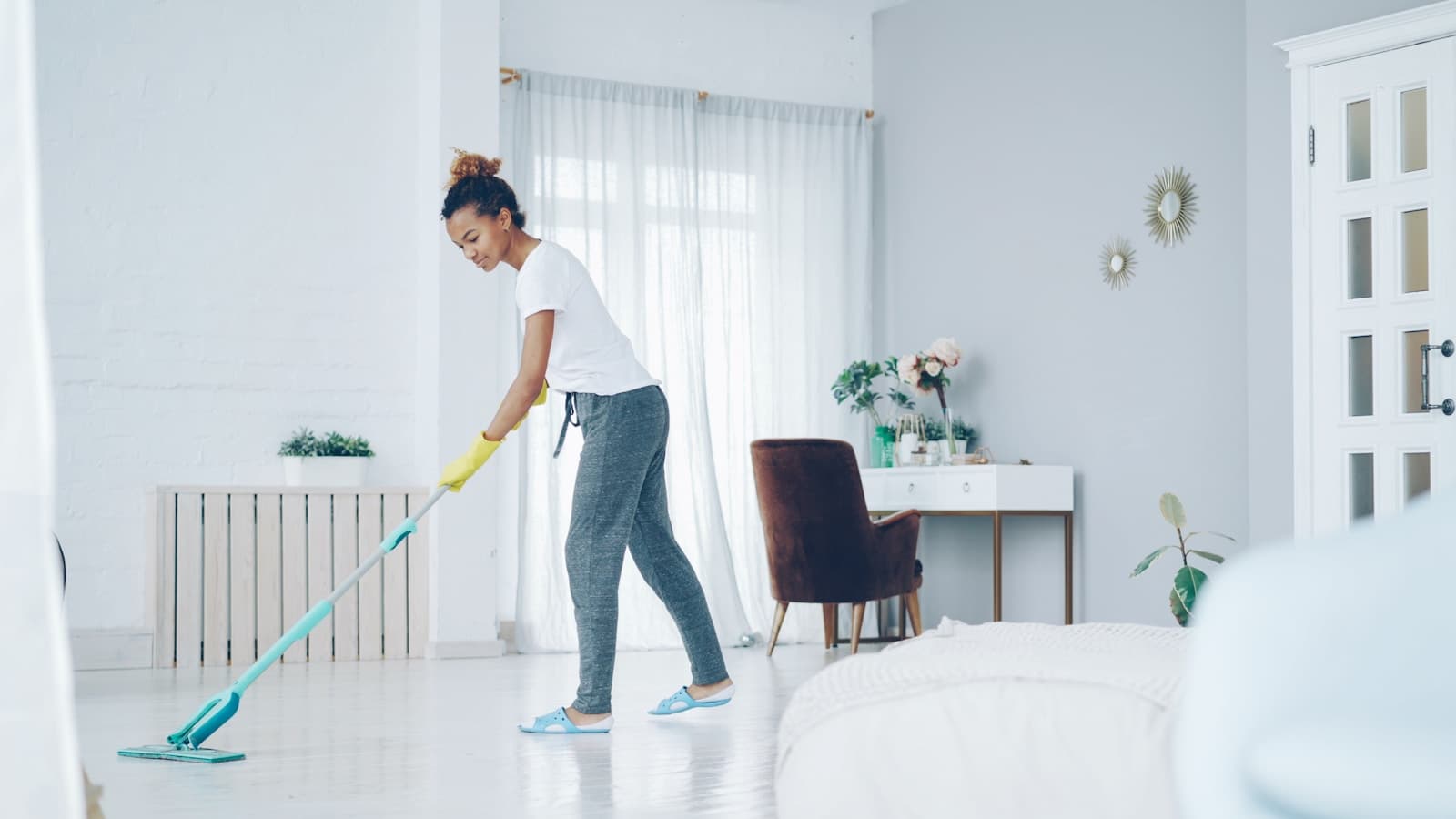 Person mopping the floor of a bright modern living room