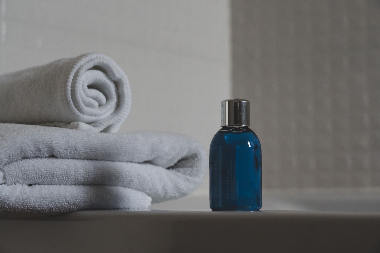 Rolled and folded white towels staged beside a bath amenity