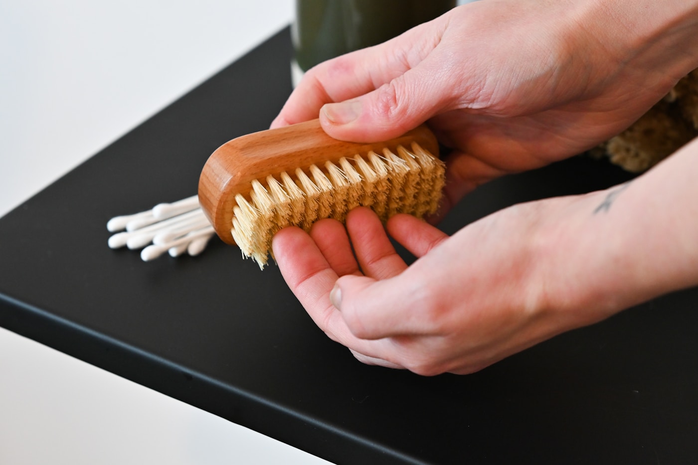 Hands holding a suede brush over a table